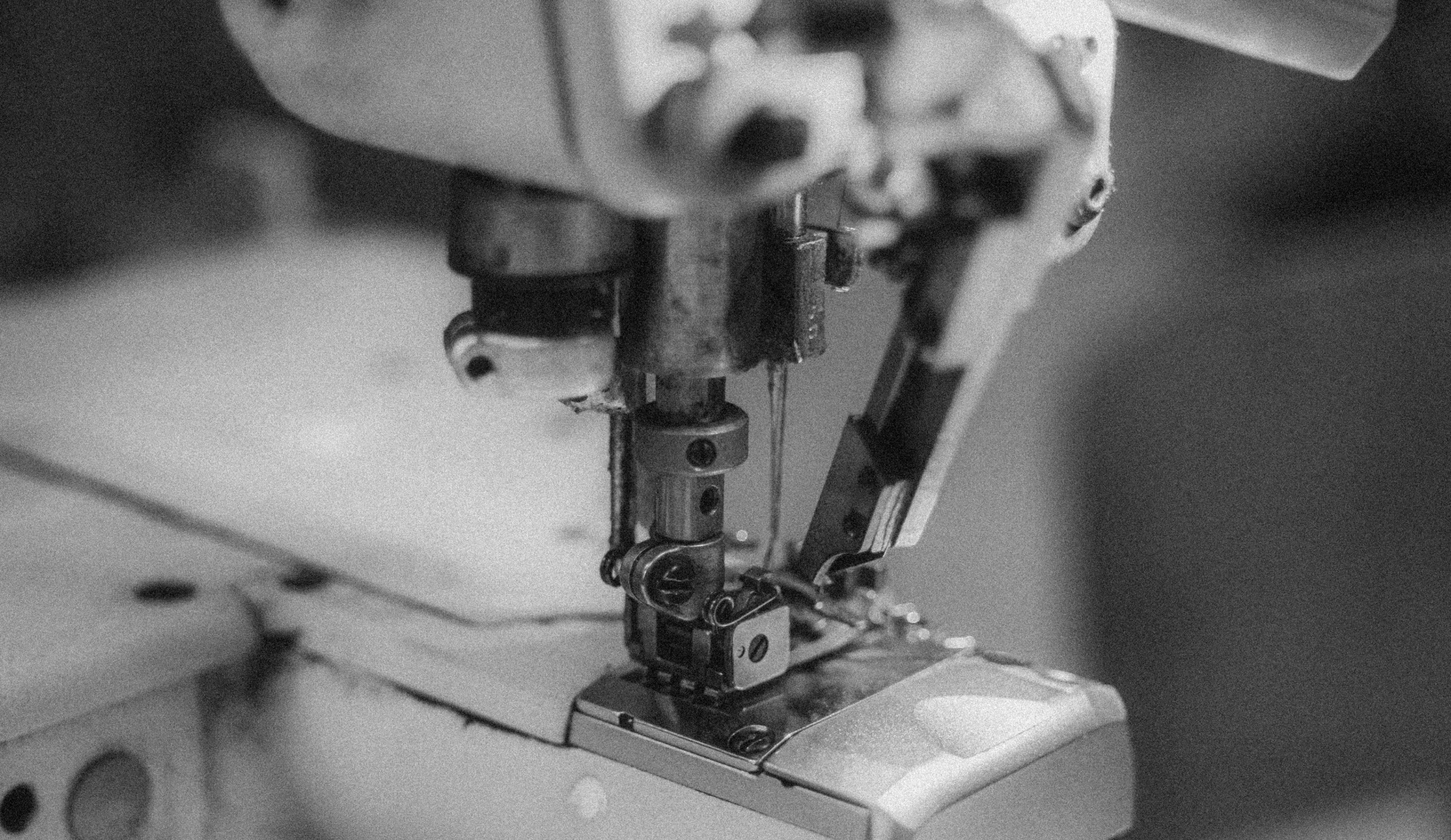 Close-up of an industrial sewing machine head in black and white