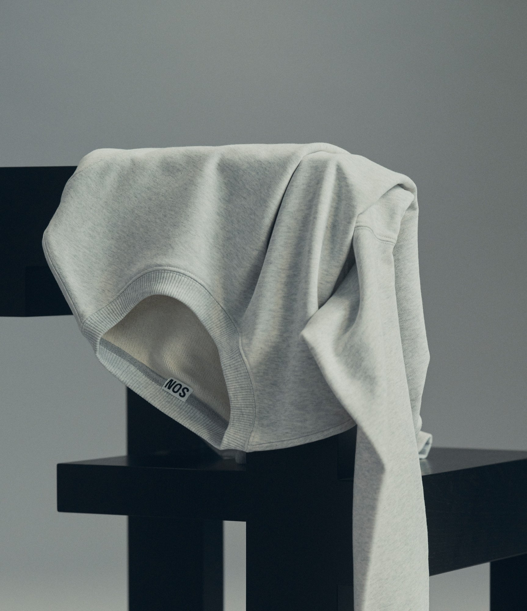 Pale grey sweatshirt draped over a black chair