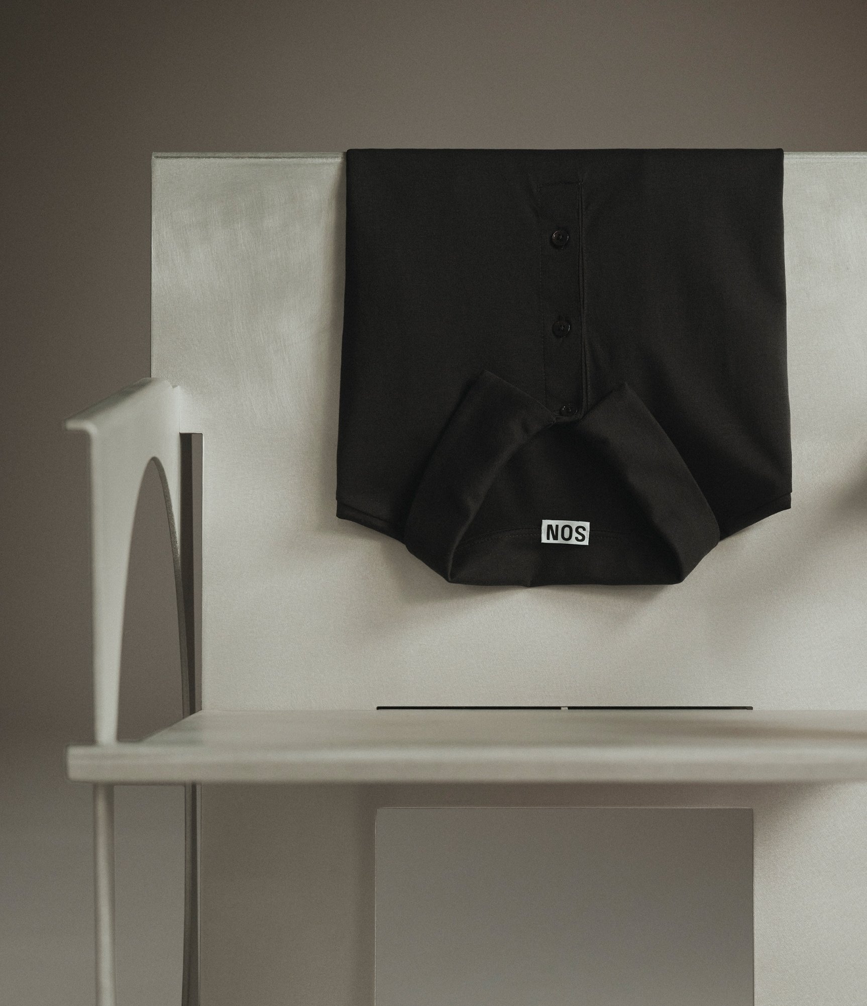 Black polo shirt laid flat on a pale table