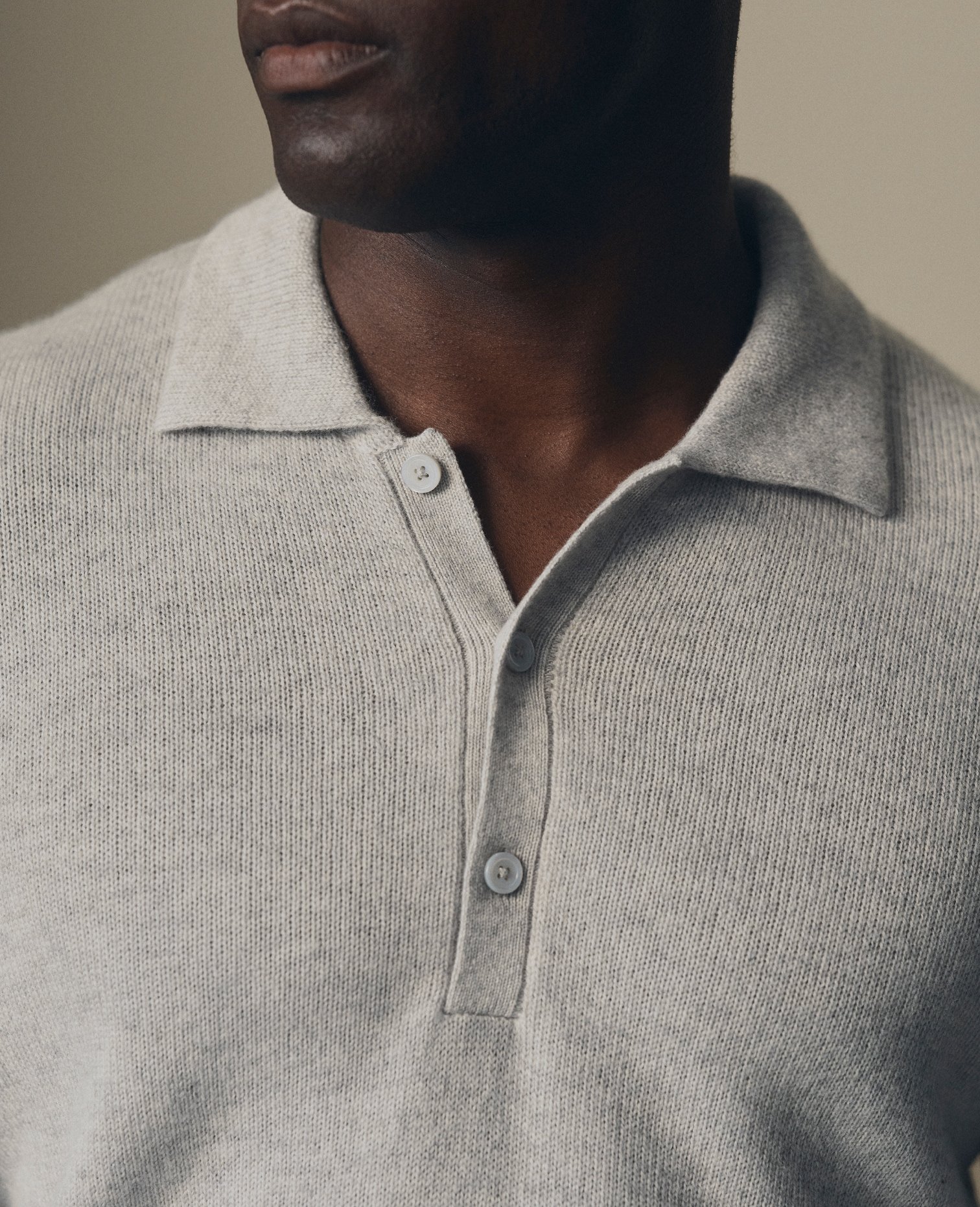 Close-up of the buttoned collar on a grey knitted polo