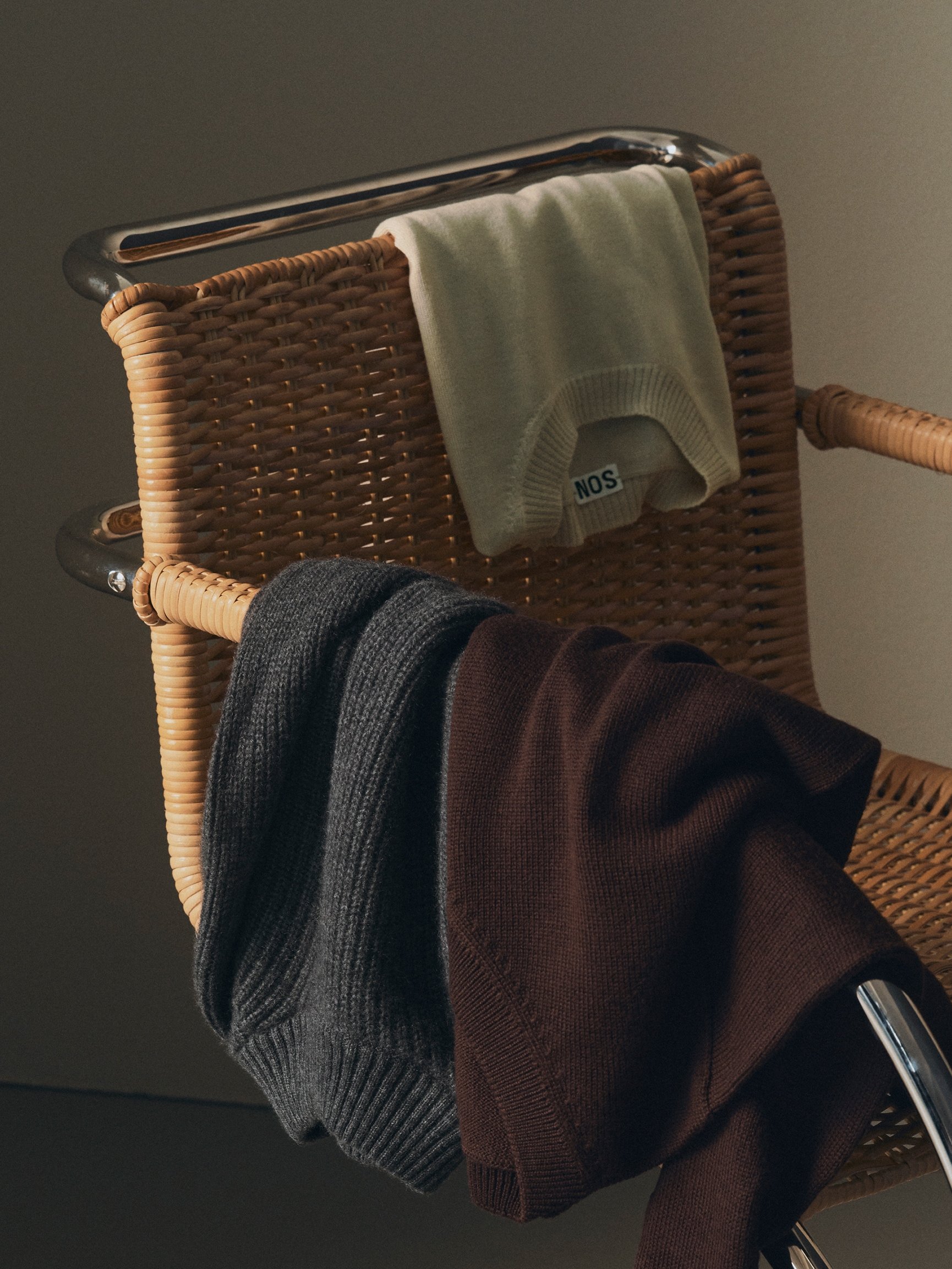 Knitwear draped over a rattan chair
