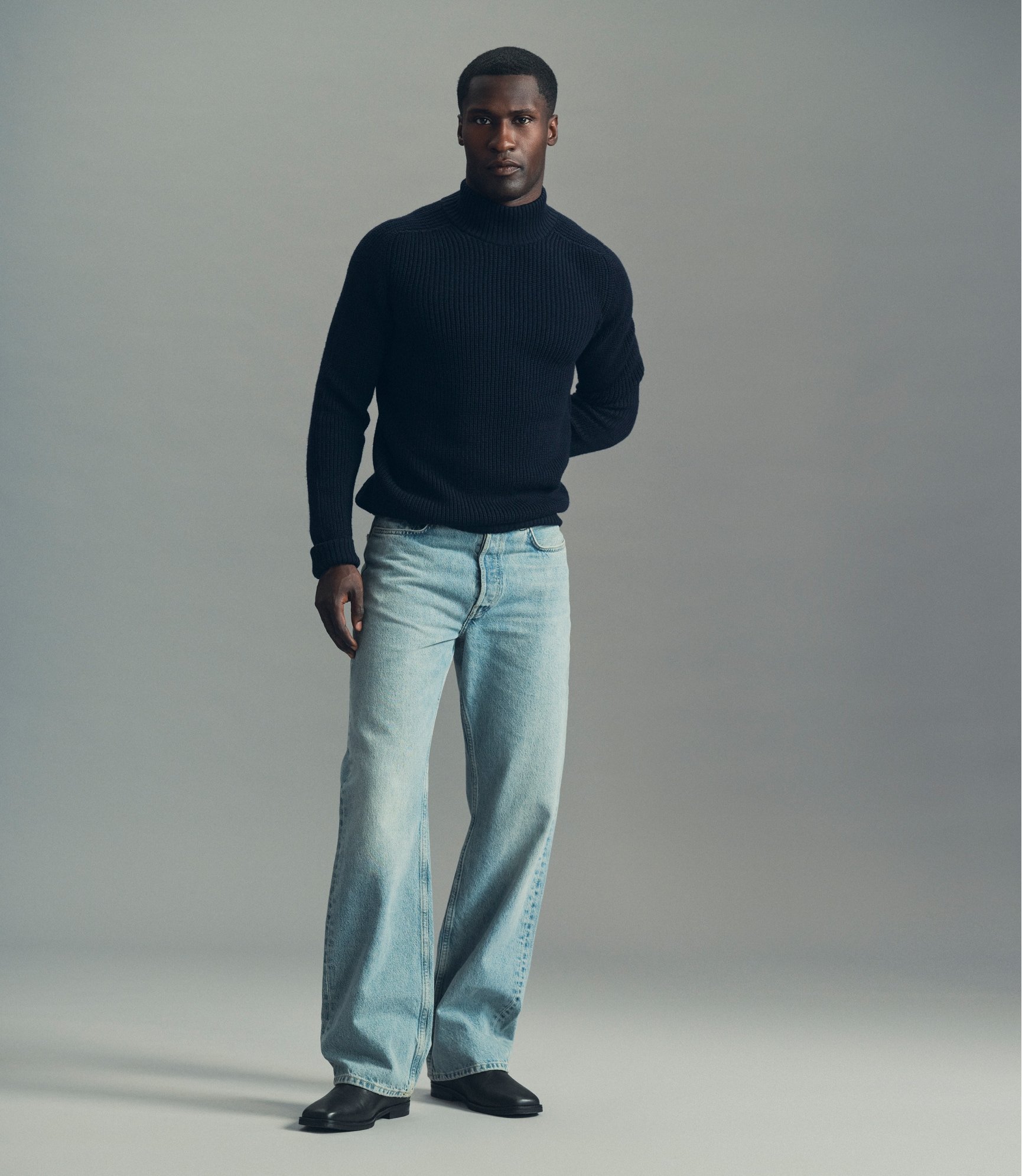 Model in a black turtleneck and light denim jeans