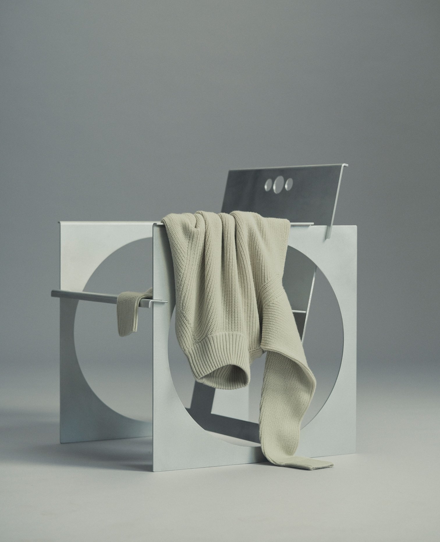 Cream knit draped over a white sculptural stand