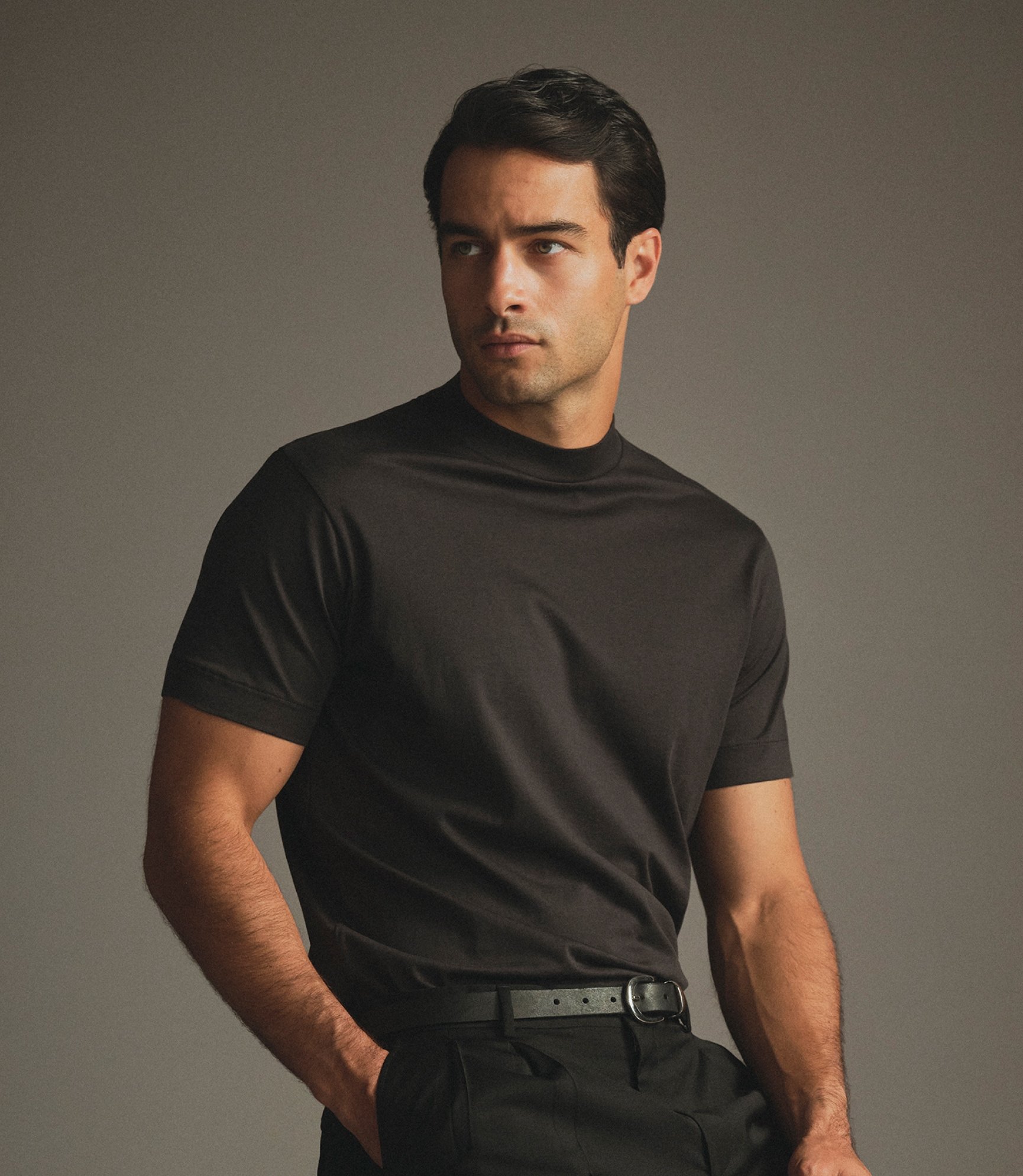 Model in a dark brown T-Shirt and black belt, hands in pockets