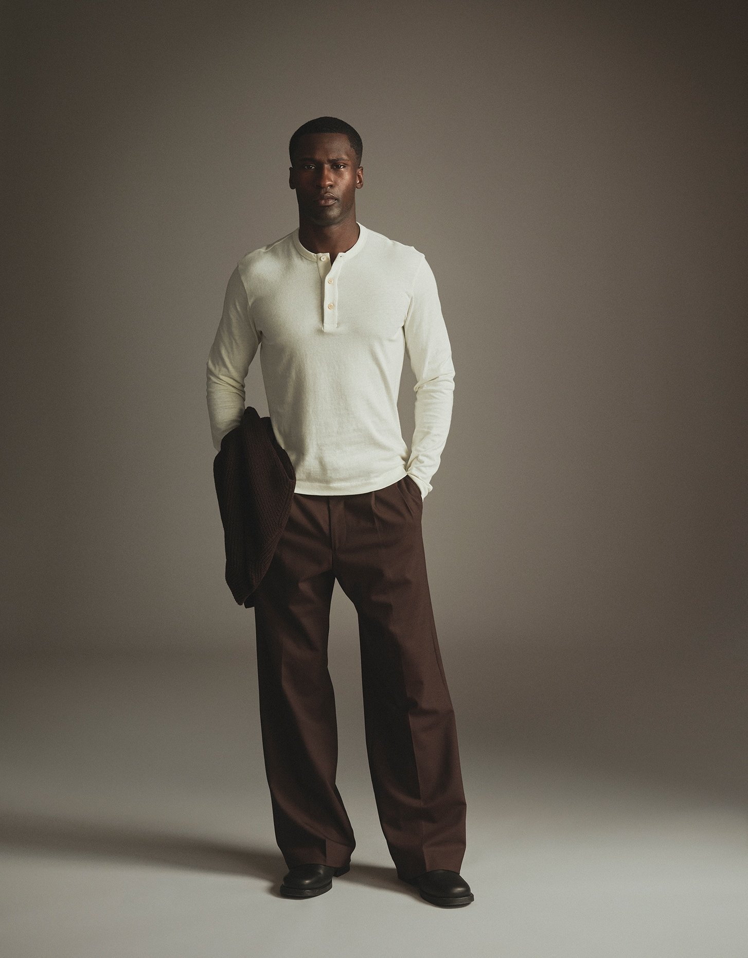 Model in a cream long-sleeve henley and brown wide-leg trousers