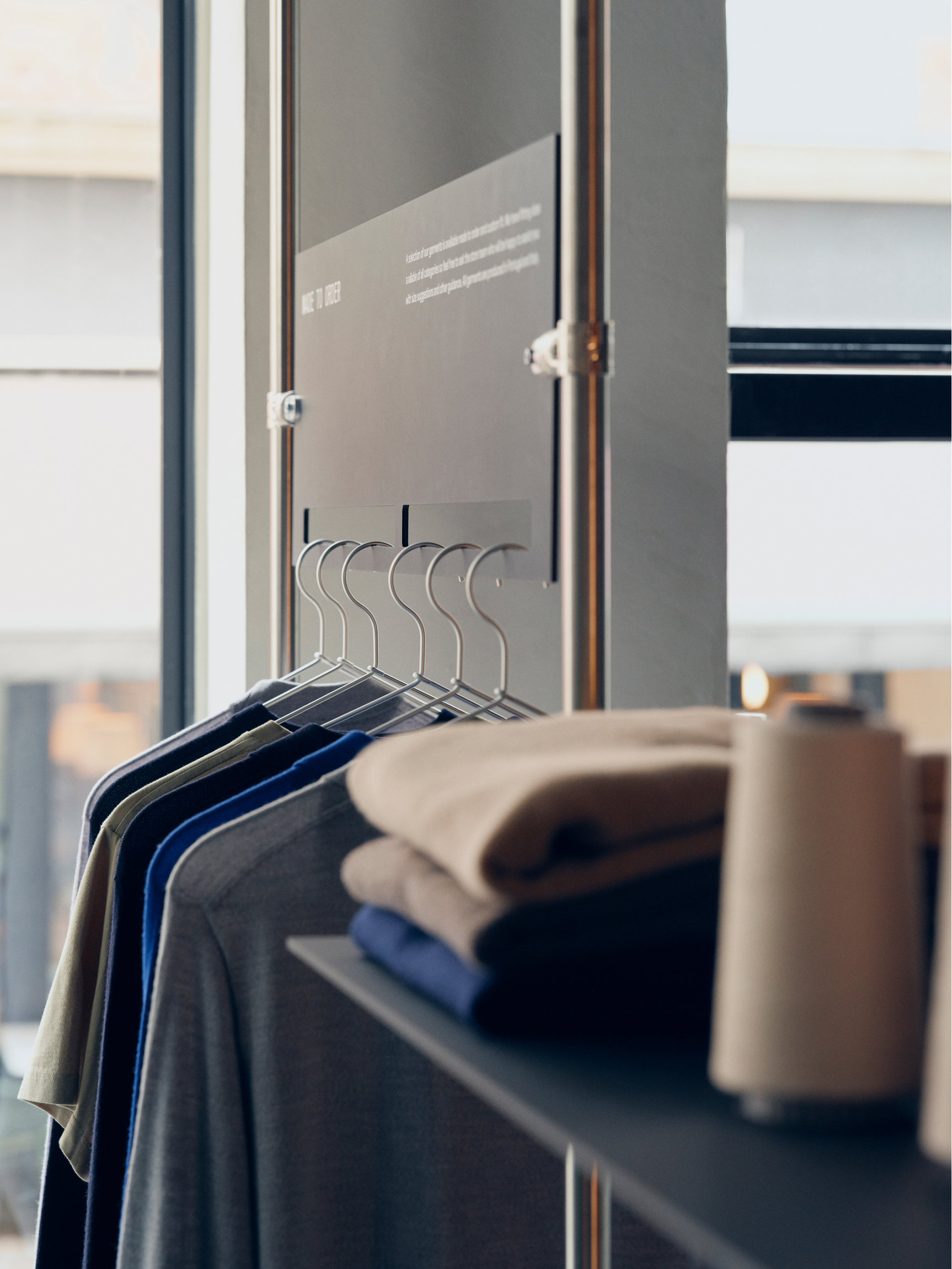 T-shirts in muted colors hanging beside folded garments in the Copenhagen store