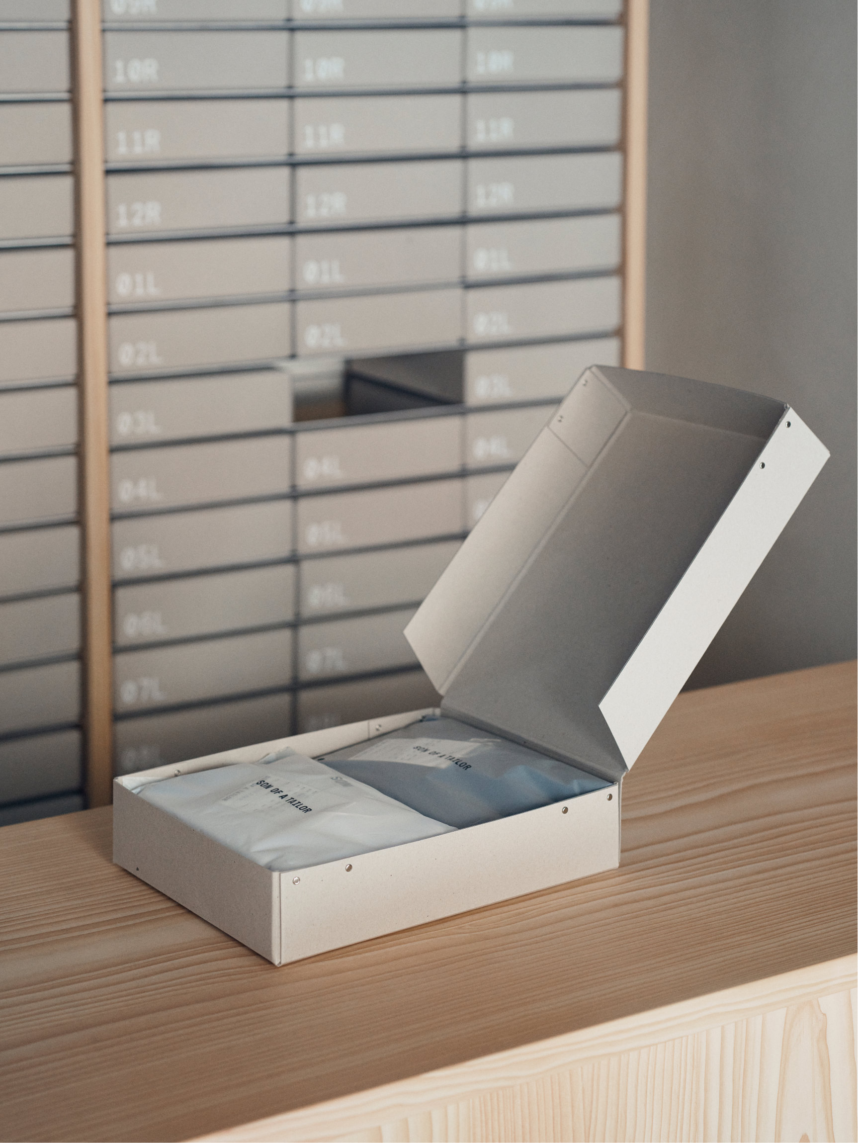 Two packaged Son of a Tailor garments in an open box on the store counter