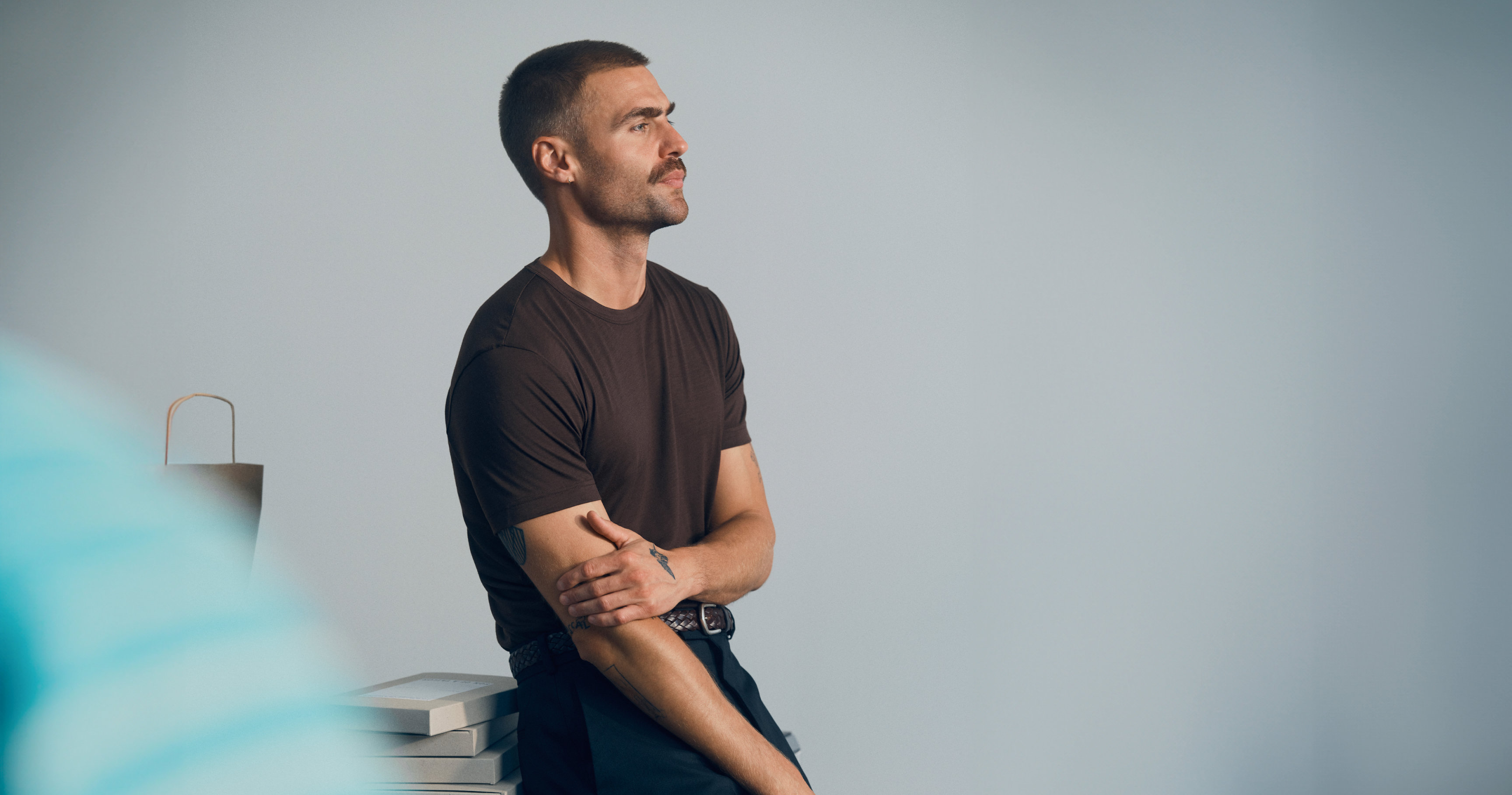 Man wearing a dark t-shirt seated beside a stack of boxes