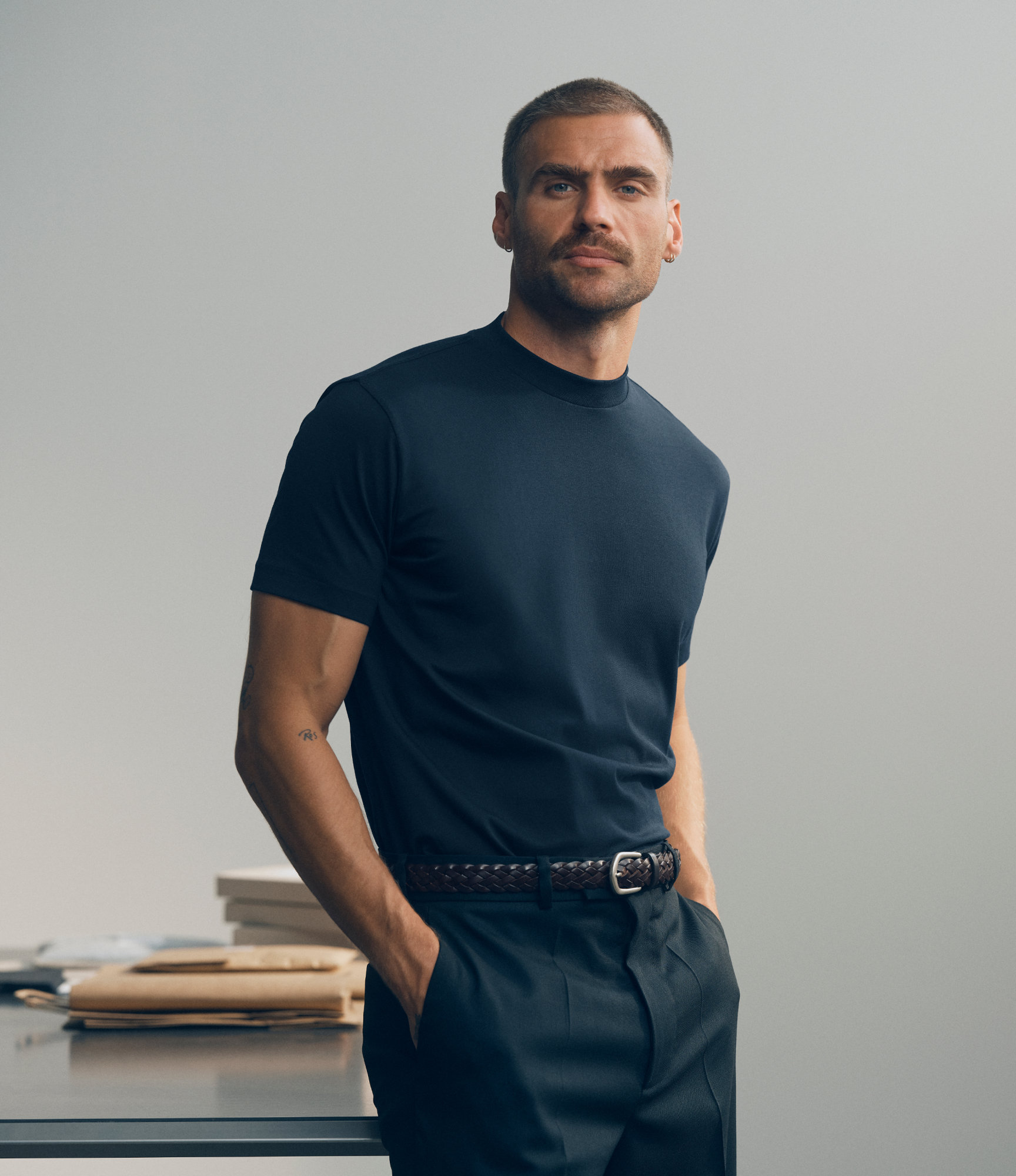 Man wearing a dark T-shirt standing beside folded garments