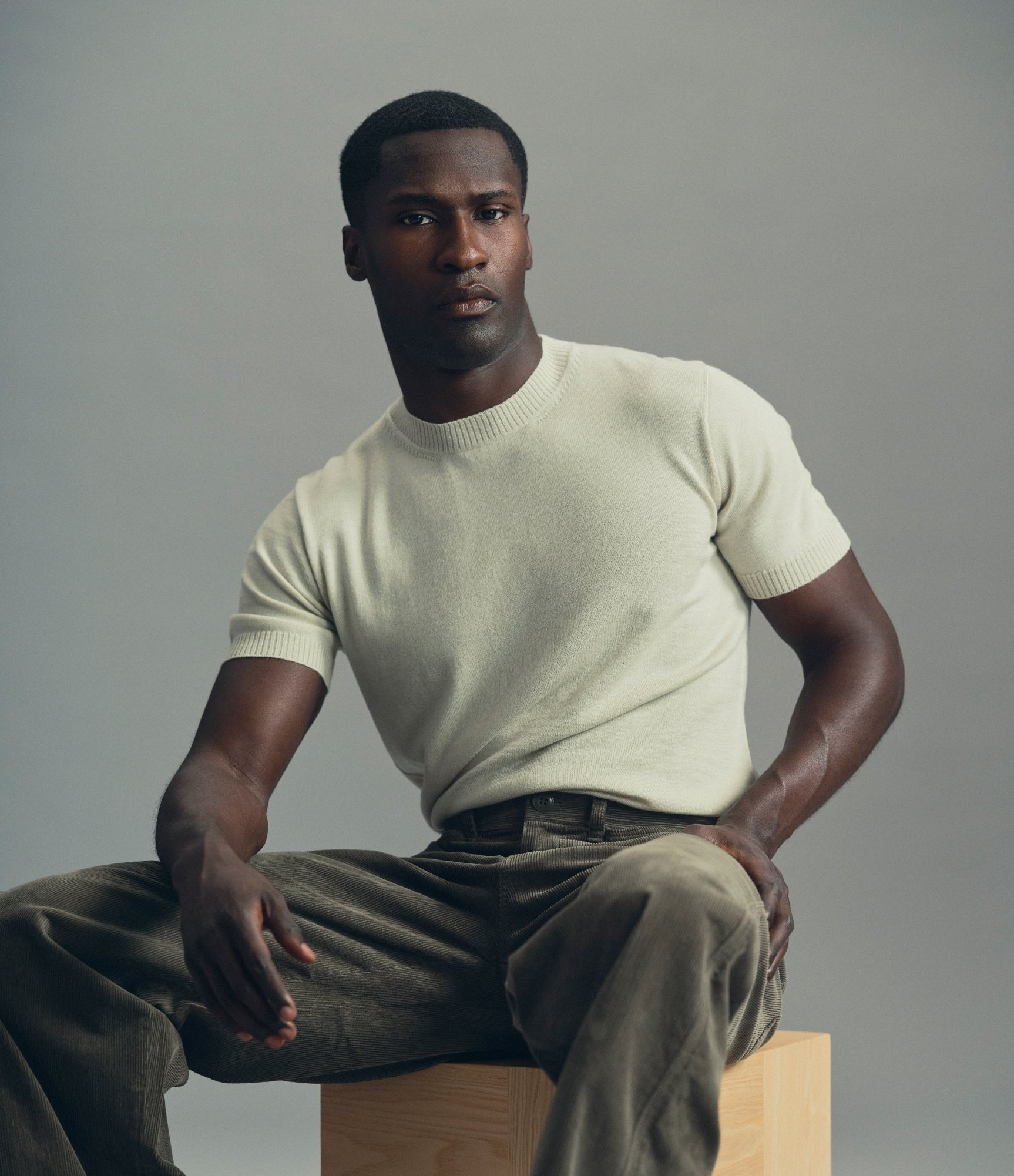 Model sitting down while wearing our Knit T-Shirt in Silver Green