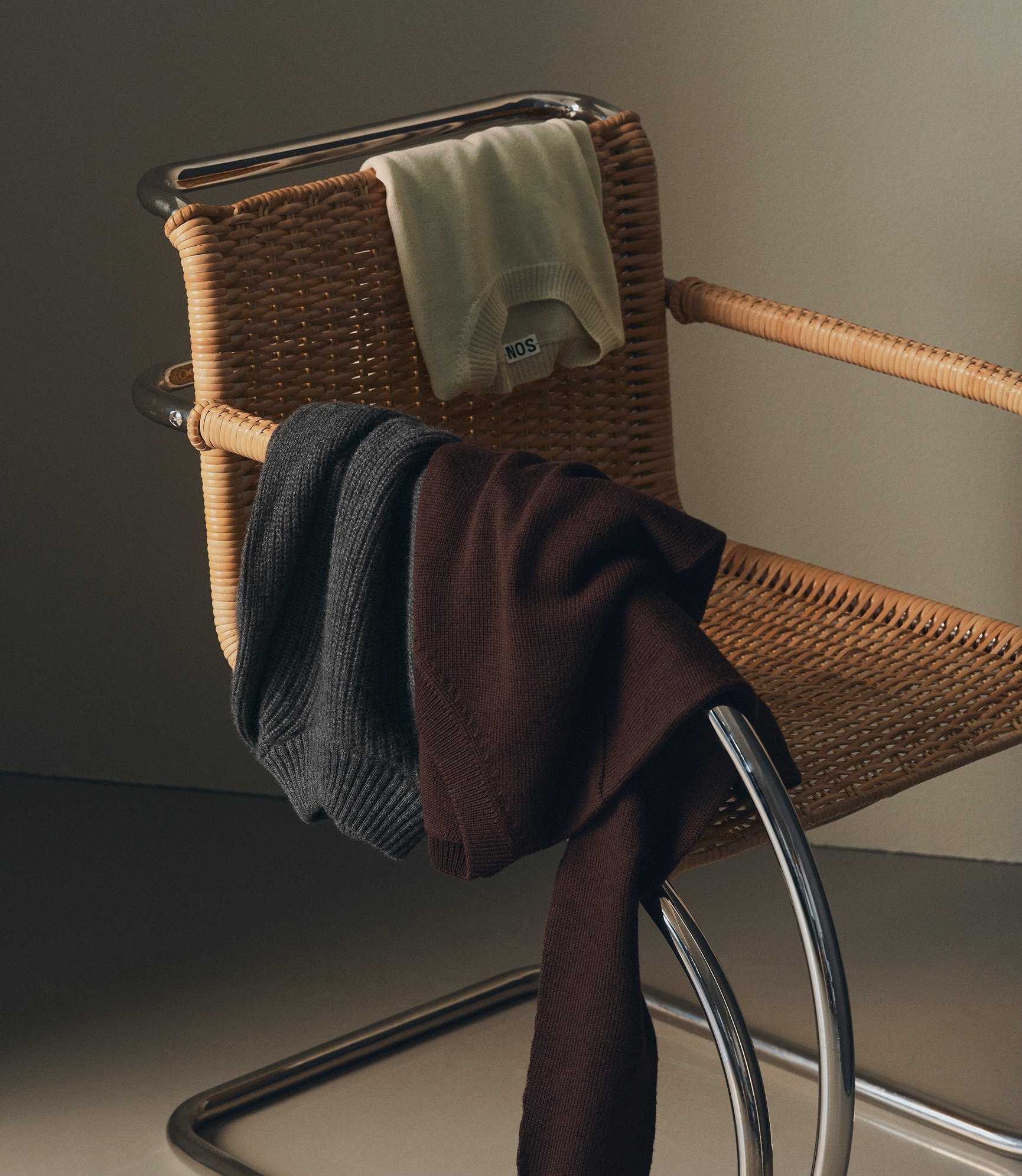 Three merino knitwear products laying on a chair