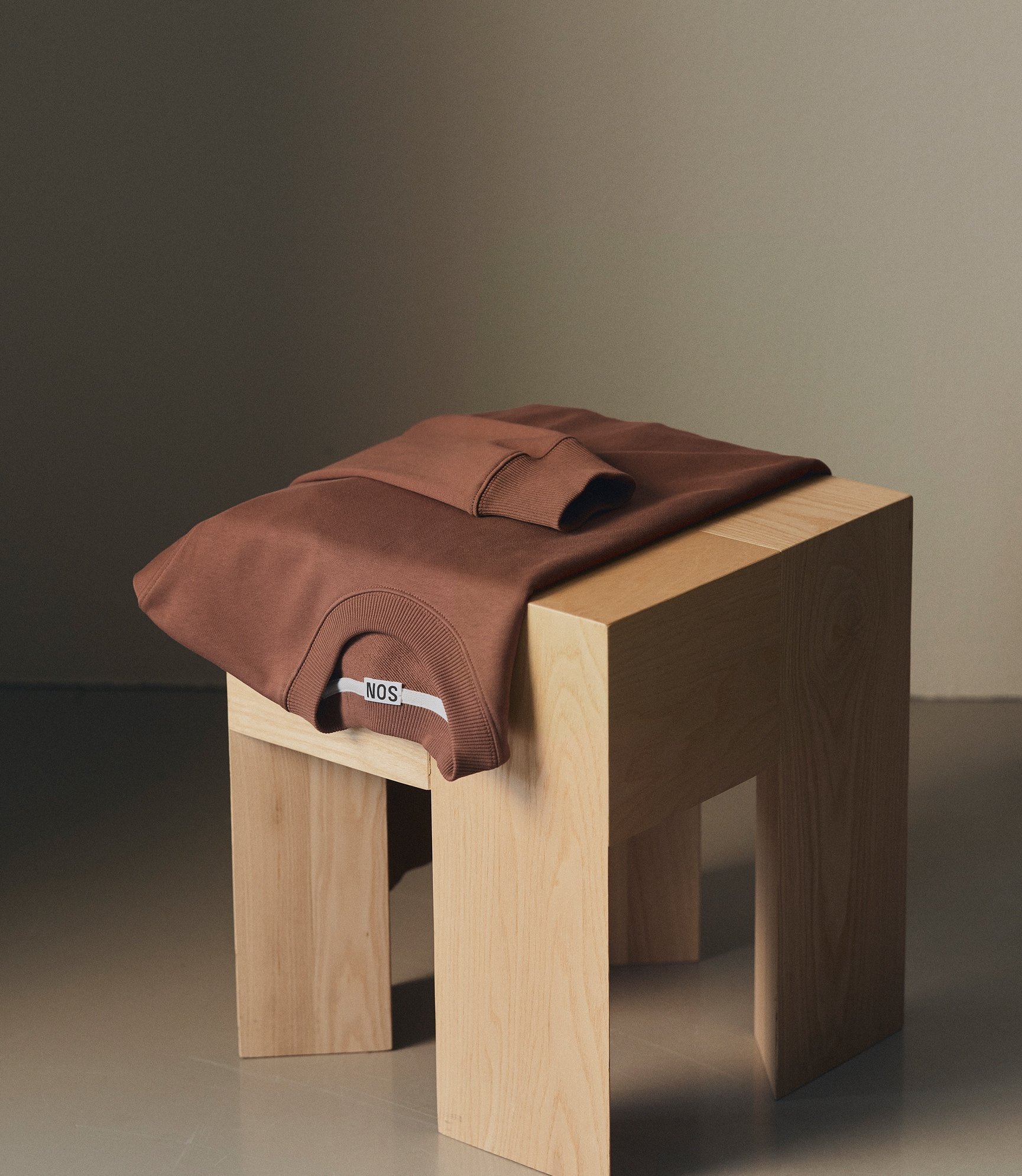 Cotton sweatshirt in mink folded on a stool