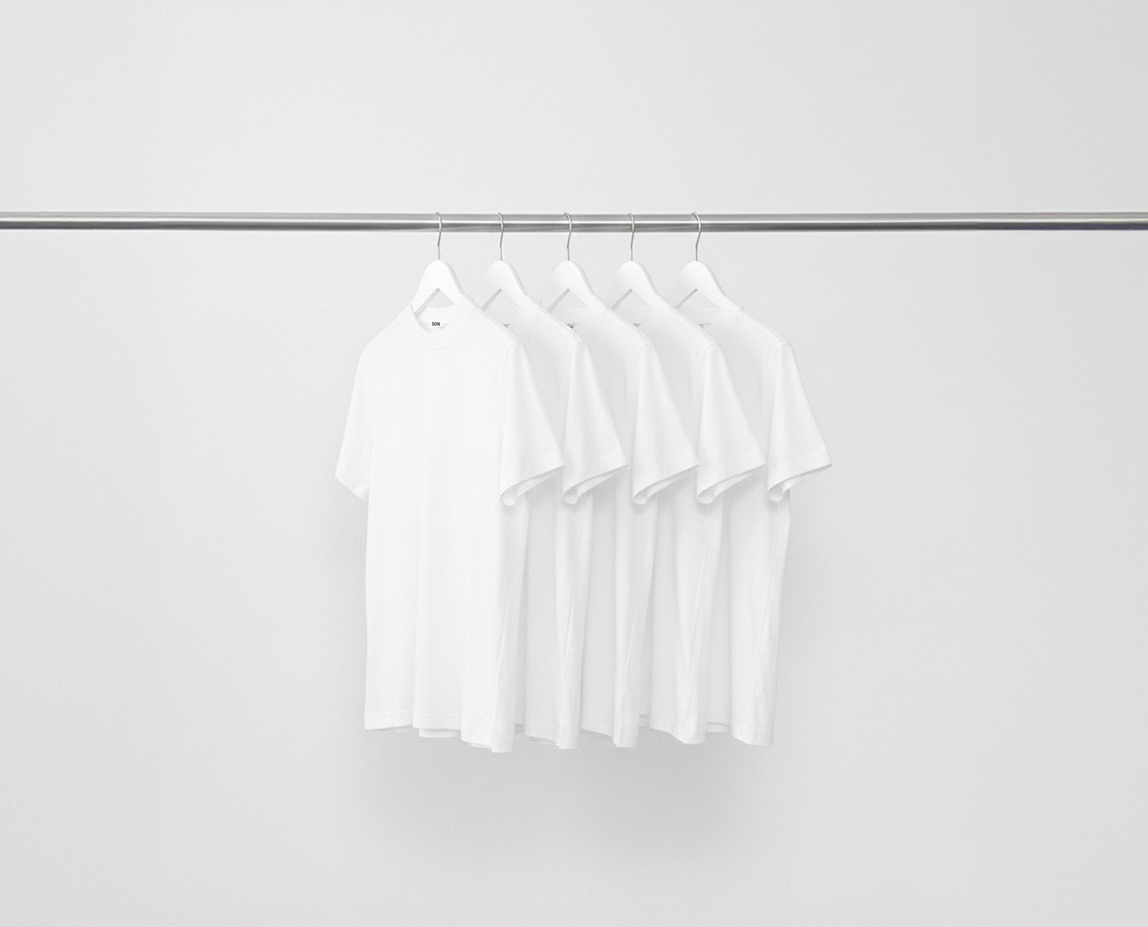 White Hi-Necks bundle t-shirts hanging on a rack against a grey background