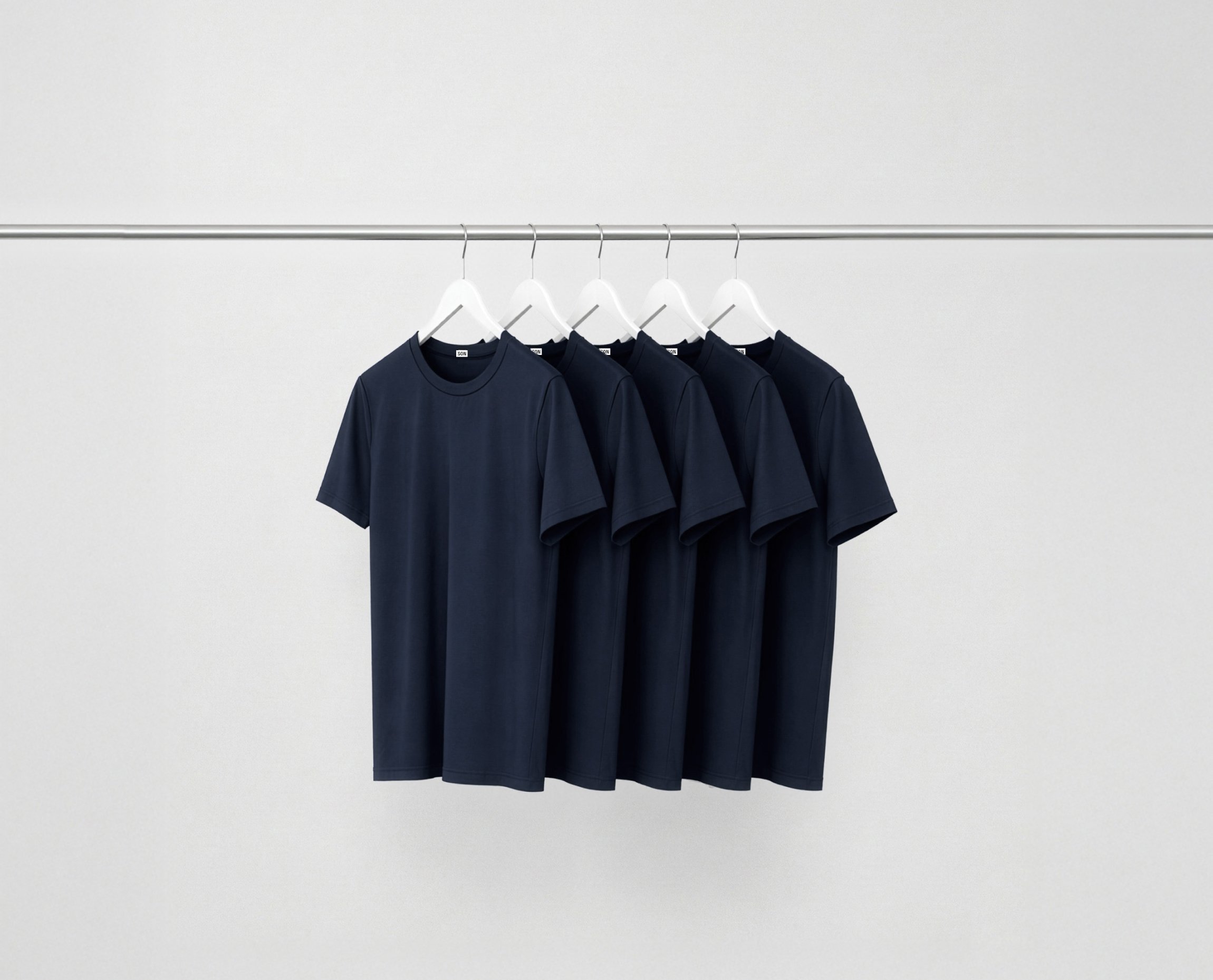 Deep blue essentials bundle t-shirts hanging on a rack against a grey background