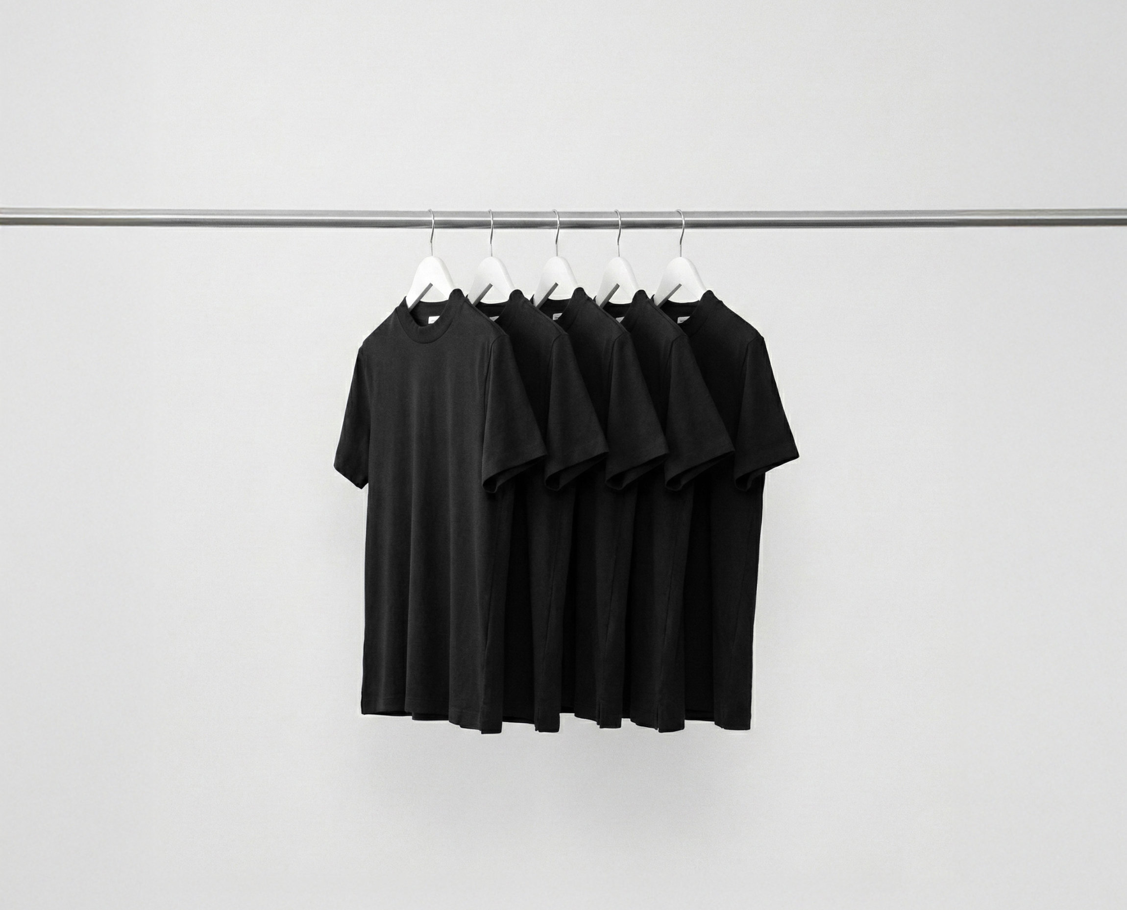 Black Hi-Necks bundle t-shirts hanging on a rack against a grey background