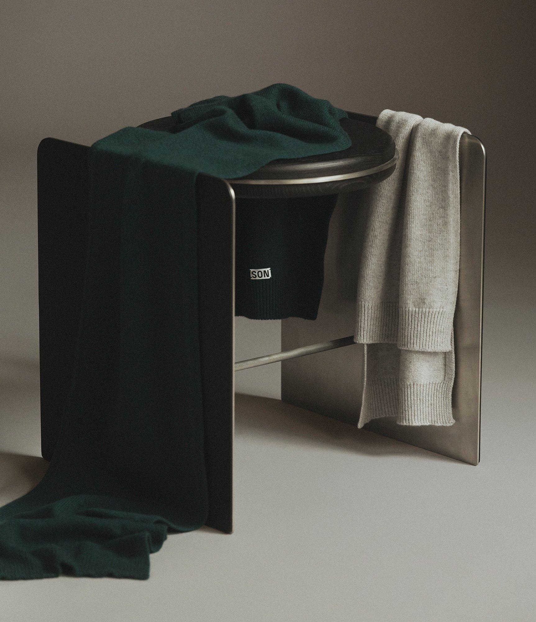 Two Cashmere Scarves in Malachite and Light Grey Melange hanging on a chair