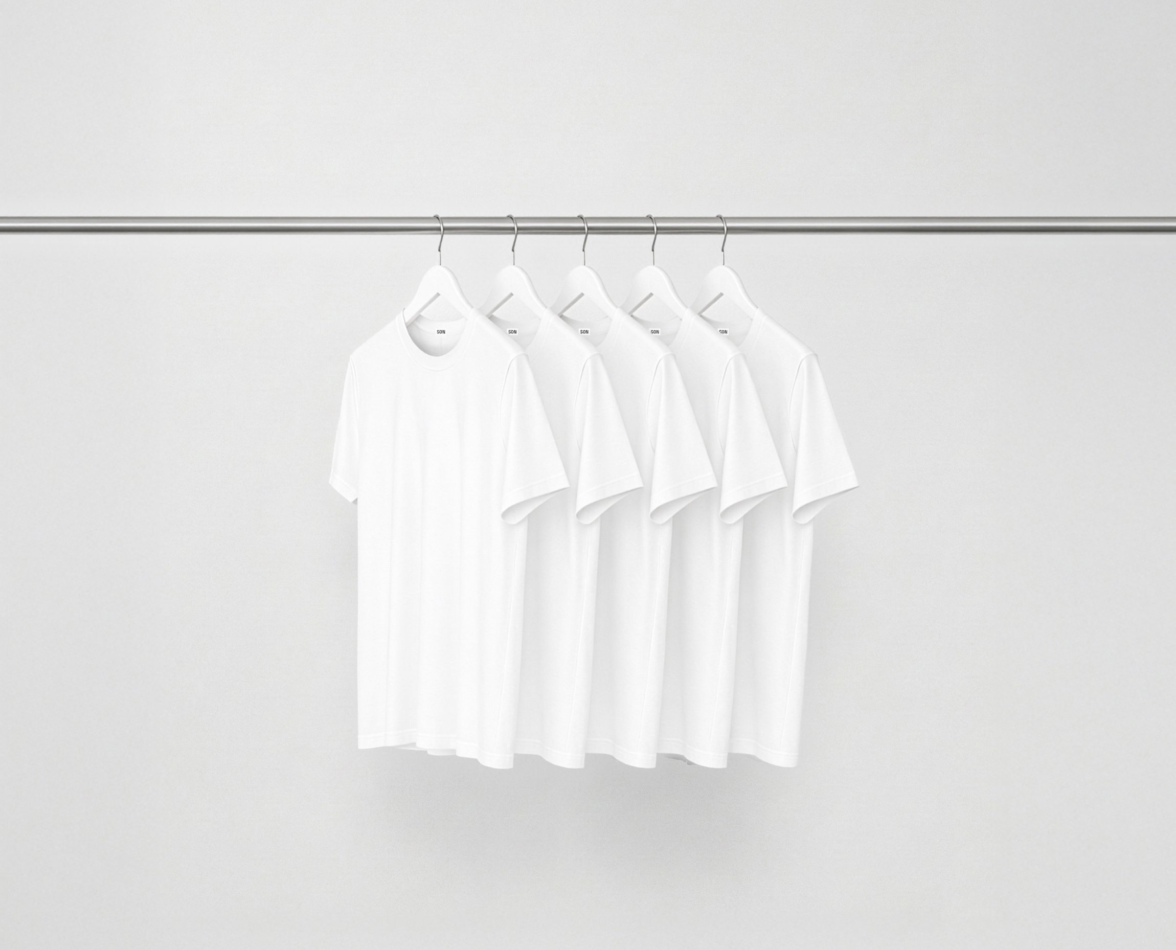 White essentials bundle t-shirts hanging on a rack against a grey background