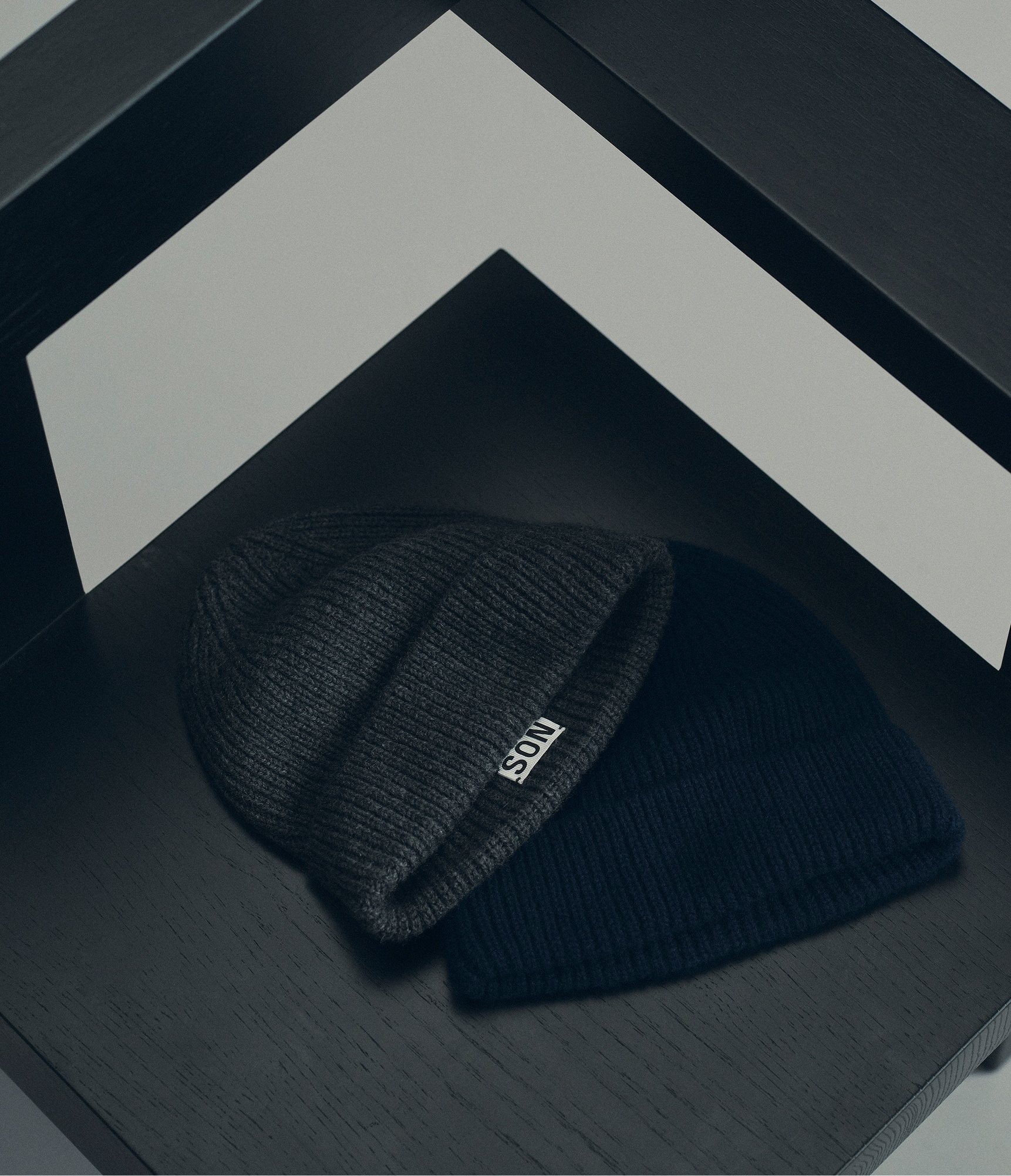 Two Cashmere Beanies in Anthracite and Navy on top of a chair