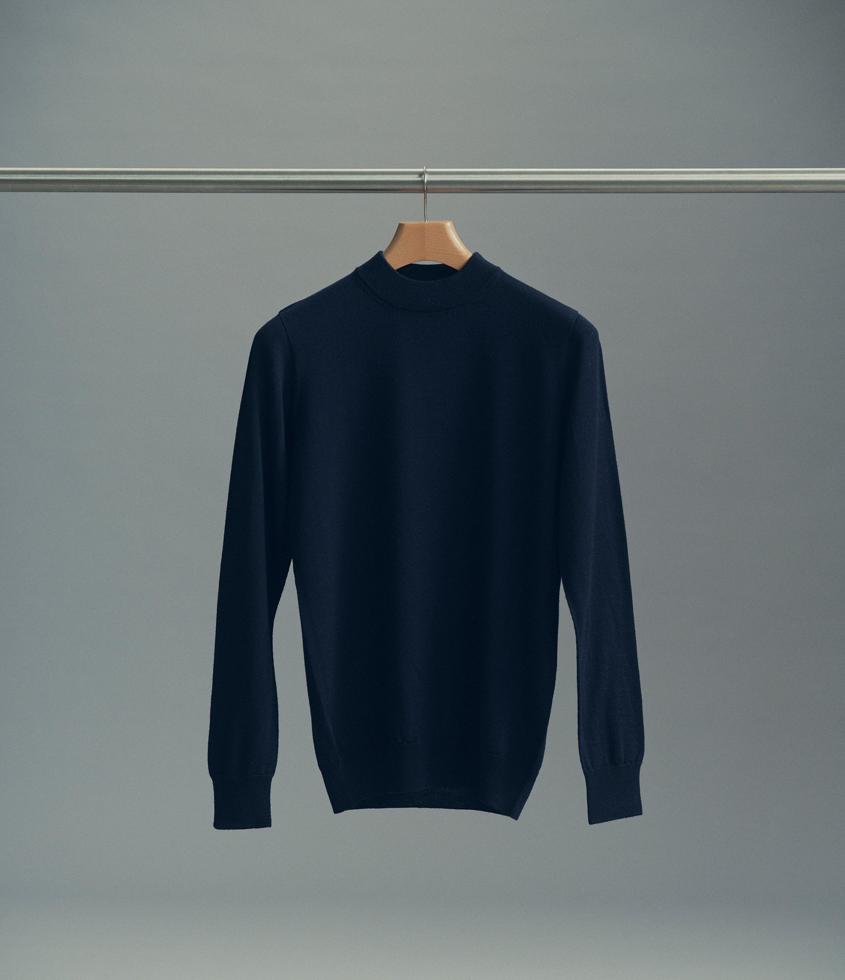 Merino hi-neck pullover in navy hanging on a rack
